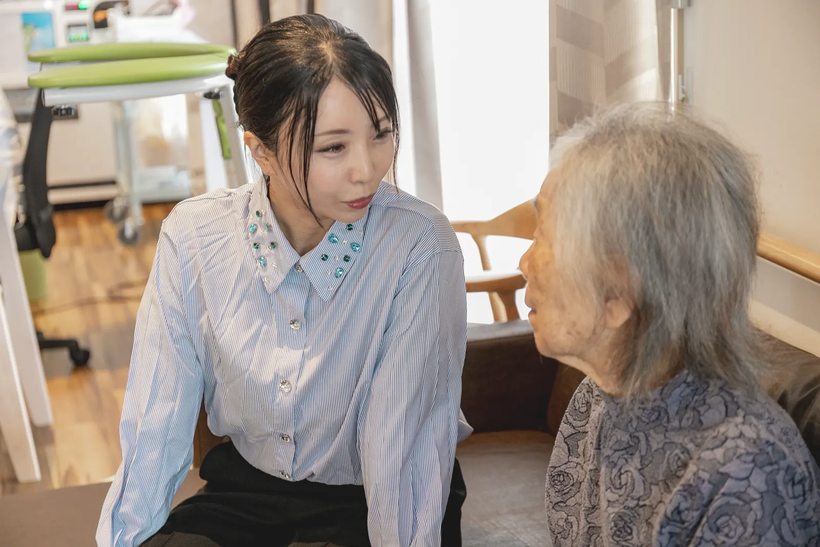 高齢の女性と並んでゆっくり話す稲津